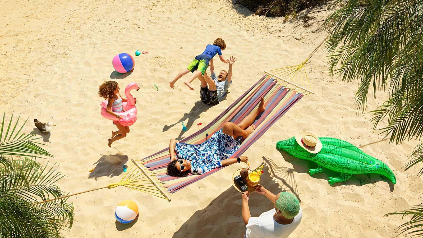 family relaxing on holiday in a hammock paying for a drink